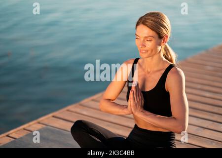 Namaste-Konzept. Porträt Einer Entspannten, Mittleren Alters Sportlichen Frau, Die Im Freien Meditiert Stockfoto