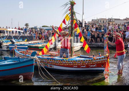 Das jährliche Fest der 'U Pisci a Mari' im sizilianischen Dorf Aci Trezza, in der Nähe von Catania. Dies findet um das Fest der Geburt des hl. Johannes des Täufers Ende Juni statt. Es handelt sich um eine traditionelle Fischereiexpedition für Schwertfisch, die früher in der Straße von Messina stattgefunden hat. Die Rolle des Schwertfisches wird von einem Schwimmer gespielt, der wiederholt von den Fischern gefangen wird, blutig aufgeschnitten wird, dann aber irgendwie entkommen kann. Schließlich schafft es der „Schwertfisch“, das Boot umzustürzen. Stockfoto