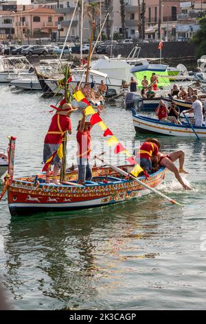 Das jährliche Fest der 'U Pisci a Mari' im sizilianischen Dorf Aci Trezza, in der Nähe von Catania. Dies findet um das Fest der Geburt des hl. Johannes des Täufers Ende Juni statt. Es handelt sich um eine traditionelle Fischereiexpedition für Schwertfisch, die früher in der Straße von Messina stattgefunden hat. Die Rolle des Schwertfisches wird von einem Schwimmer gespielt, der wiederholt von den Fischern gefangen wird, blutig aufgeschnitten wird, dann aber irgendwie entkommen kann. Schließlich schafft es der „Schwertfisch“, das Boot umzustürzen. Stockfoto