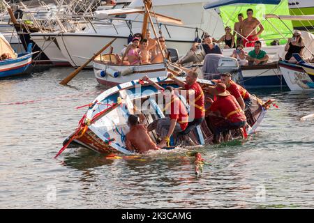 Das jährliche Fest der 'U Pisci a Mari' im sizilianischen Dorf Aci Trezza, in der Nähe von Catania. Dies findet um das Fest der Geburt des hl. Johannes des Täufers Ende Juni statt. Es handelt sich um eine traditionelle Fischereiexpedition für Schwertfisch, die früher in der Straße von Messina stattgefunden hat. Die Rolle des Schwertfisches wird von einem Schwimmer gespielt, der wiederholt von den Fischern gefangen wird, blutig aufgeschnitten wird, dann aber irgendwie entkommen kann. Schließlich schafft es der „Schwertfisch“, das Boot umzustürzen. Stockfoto