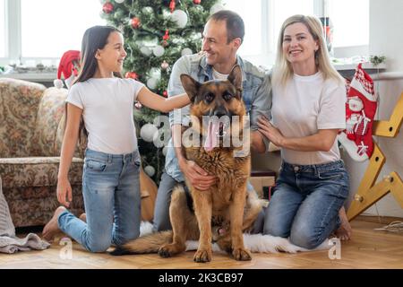 Weihnachts-Familienportrait zu Hause Urlaub Wohnzimmer, Kind und Hund spielen, Geschenk-Geschenkbox, Haus dekorieren von Xmas Tree Stockfoto