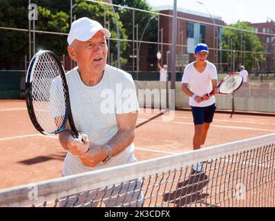 Großvater und Enkel spielen Tennisplatz Stockfoto