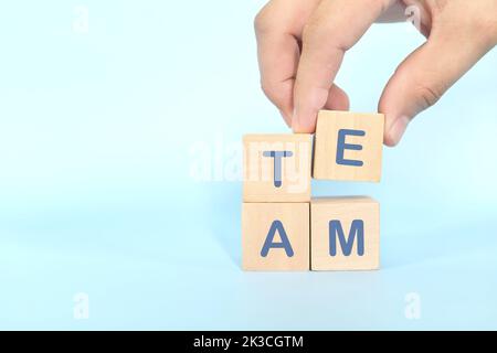 Teamwork und Teambuilding-Geschäftskonzept. Hand zusammen Holzblöcke Holz Puzzle-Stücke in blauem Hintergrund. Stockfoto