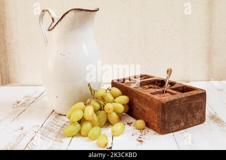 Gemischt mit Herbstfrüchten und einem Krug auf weißem Holz Platinen Stockfoto