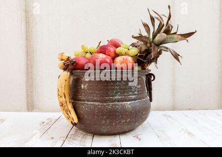 Gemischt mit Herbstfrüchten in einem Metalltopf auf einem Holzfußboden Stockfoto