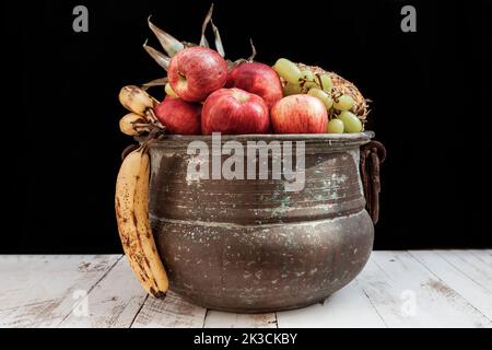 Gemischt mit Herbstfrüchten in einem Metalltopf auf einem Holzfußboden Stockfoto