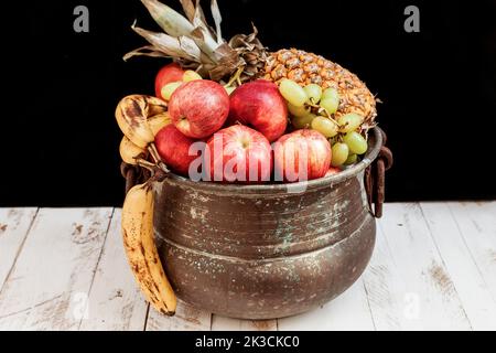 Gemischt mit Herbstfrüchten in einem Metalltopf auf einem Holzfußboden Stockfoto