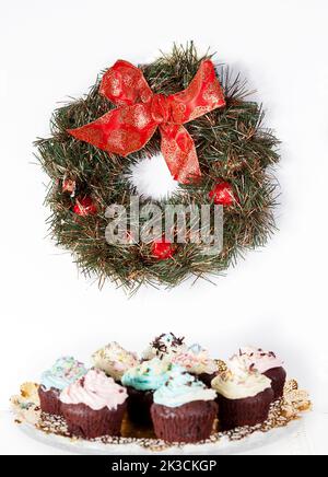 weihnachtlicher Blumenkranz auf weißem Hintergrund auf etwas Cupcake Stockfoto