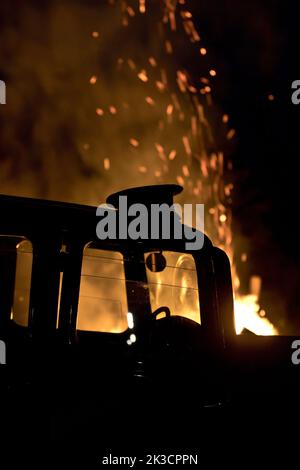 Die Kappe eines Militärs wurde auf das Dach eines 1934 Standard Ten gelegt, inmitten der flammenden Nachwirkungen des Brandbombenangriffs im Zweiten Weltkrieg. Stockfoto