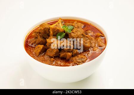 Rind-Masala oder Braten, kerala Stil hausgemachtes Rezept garniert mit Kokosnussstücken und Kerrgeblättern, die in einer weißen Schüssel mit weißem Hintergrund angeordnet ist Stockfoto
