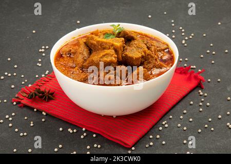 Rind-Masala oder Braten, kerala Stil hausgemachtes Rezept garniert mit Kokosnussstücken und Kerrgeblättern, die in einer weißen Schüssel mit weißem Hintergrund angeordnet ist Stockfoto