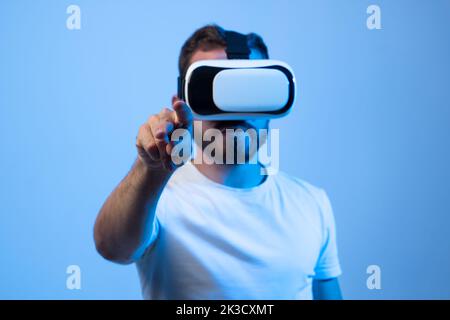 Bärtiger Mann Student in weißem T-Shirt verwendet vr Brille und versuchen, etwas mit Finger berühren, Studio Schuss. Virtuelle Gadgets für Unterhaltung, Arbeit Stockfoto