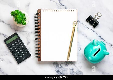 Notizblock, Sparschwein, Heimwerk, Rechner, Stift auf Marmorhintergrund Finanzplanung, Ziele, Projekt für Neujahr Konzept Draufsicht Flat Lay Finance Training und Strategien Copy space. Stockfoto