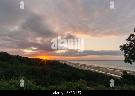 Blick über den Strand von Omaha an der französischen atlantikküste bei Sonnenuntergang mit rotem Sonnenlicht, das die Wolken berührt, Colleville-sur-Mer, Normandie, Frankreich Stockfoto