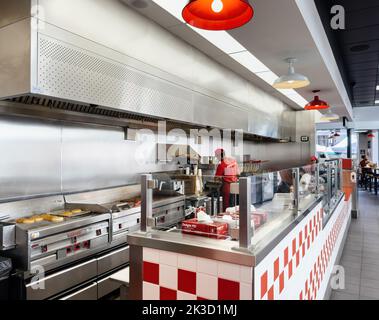 Paris, Frankreich - 21. Sep 2022: Junger Arbeiter bereitet Burger pommes frites in Inside Five Guys amerikanischen Fast-Food-Restaurantkette mit Schwerpunkt auf Hamburger, Hot Dogs und Pommes Frites zu Stockfoto