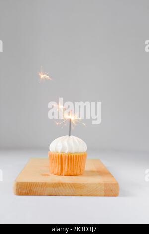 Cupcake mit weißem Zuckerguss und einem Glitzer, Geburtstagskuchen mit einem Glitzer Stockfoto