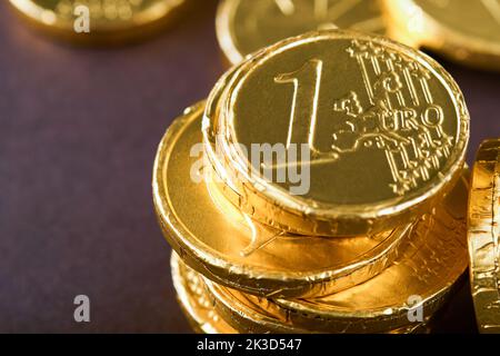 Schokoladenmünze. Hintergründe von Schokolade Euro-Münze Geld auf braunem Hintergrund. Euro-Münzen übereinander gestapelt in verschiedenen Positionen. Eine Gruppe von Münzen. Stockfoto