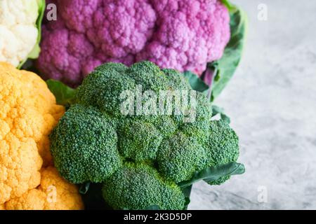 Colorfu-Blumenkohl. Verschiedene Arten von Blumenkohl auf grauem Beton Hintergrund. Violette, gelbe, weiße und grüne Farbkabbage. Brokkoli und Romanesco. Stockfoto