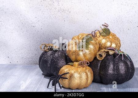 Schwarze und kaltfarbene Kürbisse auf grauem Holzhintergrund. Minimalistischer Stil Halloween Thanksgiving Hintergrund Kopie Raum Stockfoto