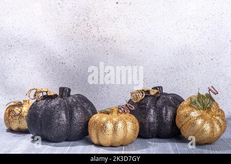 Schwarze und kaltfarbene Kürbisse auf grauem Holzhintergrund. Minimalistischer Stil Halloween Thanksgiving Hintergrund Kopie Raum Stockfoto