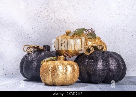 Schwarze und kaltfarbene Kürbisse auf grauem Holzhintergrund. Minimalistischer Stil Halloween Thanksgiving Hintergrund Kopie Raum Stockfoto