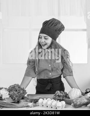 Happy teen Mädchen Kochen Gemüse. Kind trägt professionelle Koch Uniform. Stockfoto