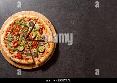 Vegetarische Pizza mit Zucchini, Tomaten, Paprika und Pilzen auf schwarzem Stein. Draufsicht. Speicherplatz kopieren Stockfoto