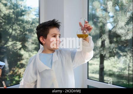 Intelligentes Kind, Schüler Chemiker Wissenschaftler hält eine Flasche mit Chemikalien, Durchführung von Experimenten in Chemie Klassenzimmer Stockfoto