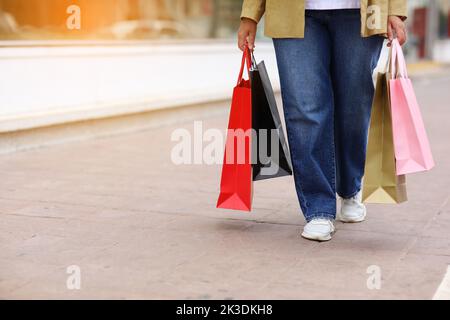 Ein kurzer Schnitt von einer nicht erkennbaren Frau mit bunten Einkaufstaschen im Hintergrund eines städtischen Einkaufszentrums. Käufe, schwarzer freitag, Rabatte, Verkaufskonzept. Onli Stockfoto