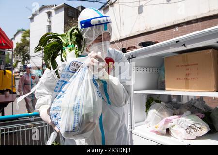 Peking, Chinas Provinz Hunan. 7. April 2022. Ein Freiwilliger lädt in der Gemeinde Fengshushan in Changsha, der zentralchinesischen Provinz Hunan, den täglichen Bedarf auf ein fahrerloses Fahrzeug, 7. April 2022. Quelle: Chen Sihan/Xinhua/Alamy Live News Stockfoto