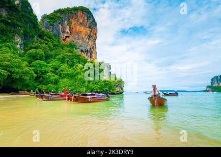 Der berühmte Railay Strand in Krabi, Thailand. Langschwanzboote werden für Passagiere in der Nähe von Kalksteinfelsen vorbereitet. Tropisches Paradies, berühmter touristischer Desti Stockfoto