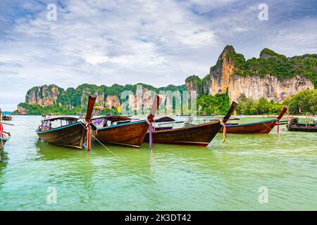 Der berühmte Railay Strand in Krabi, Thailand. Langschwanzboote werden für Passagiere in der Nähe von Kalksteinfelsen vorbereitet. Tropisches Paradies, berühmter touristischer Desti Stockfoto