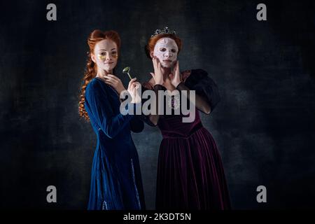 Portrait von zwei schönen Frauen in Bild von Königin und Prinzessin Anwendung Gesichtsmasken. Hautpflegeprogramm Stockfoto