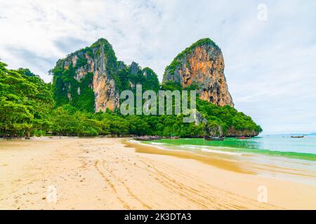 Der berühmte Railay Strand in Krabi, Thailand. Langschwanzboote werden für Passagiere in der Nähe von Kalksteinfelsen vorbereitet. Tropisches Paradies, berühmter touristischer Desti Stockfoto