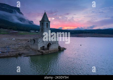 Glockenturm von Sau während der Dürre von 2022 vollständig ausgesetzt. Roter Sonnenaufgang im Sumpf (Osona, Barcelona, Katalonien, Spanien) ESP: Campanario de Sau Stockfoto