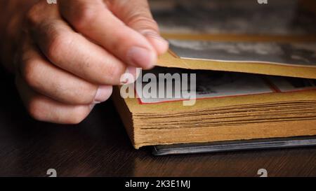 Nahaufnahme der Hände eines älteren Mannes, der alte Familienfotos in seinem Haus ansieht. Stockfoto