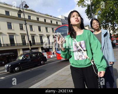 London, England, Großbritannien. Junge asiatische Frau mit einem Mobiltelefon in The Strand Stockfoto