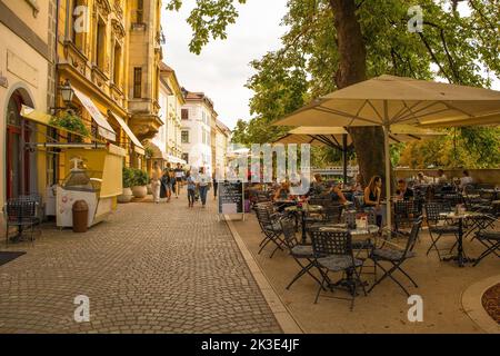 Ljubljana, Slowenien - September 3. 2022. Eine verkehrsreiche Fußgängerzone mit Bars und Restaurants an der Uferpromenade des Flusses Ljubljanici Stockfoto