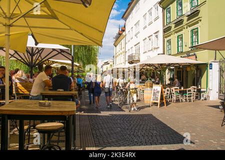 Ljubljana, Slowenien - September 4. 2022. Eine verkehrsreiche Fußgängerzone mit Bars und Restaurants an der Uferpromenade des Flusses Ljubljanici Stockfoto