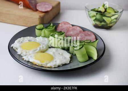 Zastrak-Eier Rühreier Wurst Salat Gurken auf der Trael Blick von der Seite oben. Traditionelles englisches amerikanisches Frühstück. Erste Mahlzeit. Das Benef Stockfoto