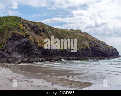 Blick auf die Klippen vom Warren Beach. Die felsige Küste im Süden Irlands. Hügel unter dem Himmel an einem Frühlingstag, Berg am Meer. Stockfoto