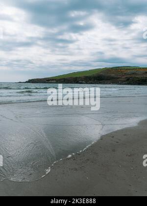 Blick auf den Rosscarbery Pier vom Warren Beach, Südküste Irlands. Wellen an einem Sandstrand. Der Atlantik bei bewölktem Wetter. Dramatische Landschaft. Stockfoto