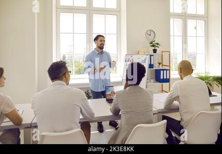 Team von Mitarbeitern, die während eines Meetings mit einem professionellen Business Coach am Bürotisch sitzen Stockfoto