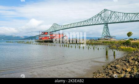 Astoria, OR, USA - 14. September 2022; Astoria Megler Bridge über den Columbia River zwischen Oregon und Washington und über der roten Boutique Cannery Stockfoto