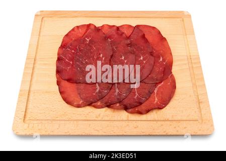 Bresaola Scheiben, italienische getrocknete Rindersalami aus Valtellina auf Holzschneidebrett isoliert auf weiß Stockfoto