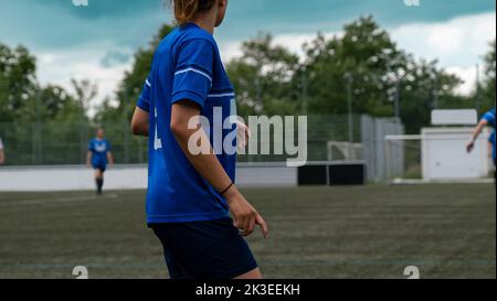 Fußballspielerin in einem Spiel mit anderen Fußballspielern im Hintergrund an einem Sommertag Stockfoto