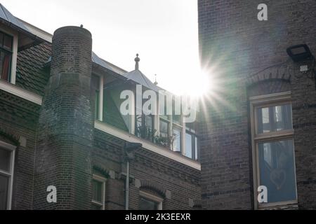 Sonnenstern zwischen alten niederländischen Häusern in einem versteckten Viertel von Amsterdam Stockfoto