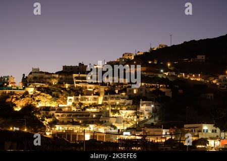 Atemberaubende Aussicht auf luxuriöse und beleuchtete weiß getünchte Hotels mit Balkon in iOS Griechenland bei Sonnenuntergang Stockfoto