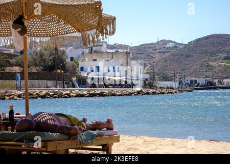 IOS, Griechenland - 12. September 2022 : Touristen entspannen sich auf Sonnenliegen am Strand von Gialos in iOS Griechenland Stockfoto