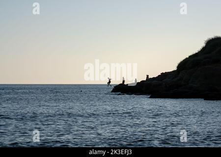 Touristen springen von einer Klippe am Mylopotas Strand in iOS Griechenland Stockfoto